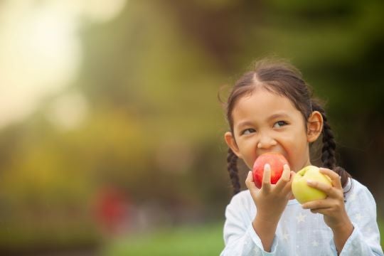 Girl Eating Apple Close-up of girl eating apples near trees.